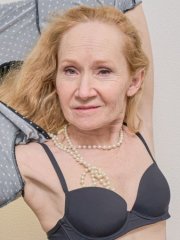 Slim mature redhead Izen strips naked and rubs her pussy in the bedroom